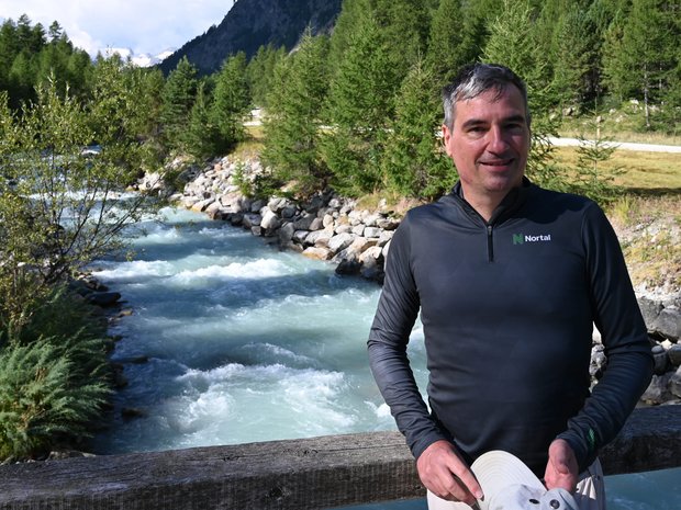 Florian is standing on a bridge over a stream in a valley.